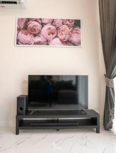 TV en la sala de estar con rosas rosas en la pared en Kanchanaburi Modern Home en Kanchanaburi