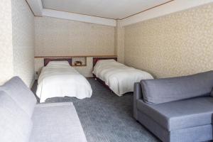 ein Hotelzimmer mit 2 Betten und einem Sofa in der Unterkunft Kogakuro in Myōkō