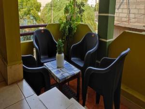 três cadeiras e uma mesa com um vaso de plantas numa varanda em La nest residency em Pondicherry
