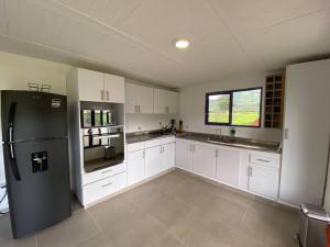 eine Küche mit weißen Schränken und einem schwarzen Kühlschrank in der Unterkunft Life is Beautiful! Cottage in the Nature in Pereira
