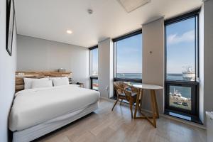 1 dormitorio con cama, mesa y ventanas en Stay Hostel, en Sokcho