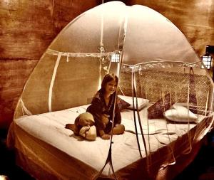 Eine Frau, die auf einem Bett mit einem Teddybären sitzt. in der Unterkunft Woody Cabana in Trincomalee