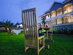 a wooden chair sitting in the grass in front of a house at Stargate Apartments in Arusha +6 photos
