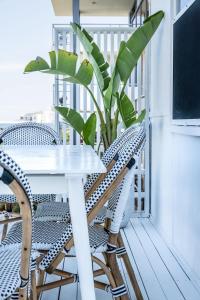een witte tafel en stoelen op een balkon met een plant bij Kings Beach Coastal Getaway, Bring the dog! in Caloundra