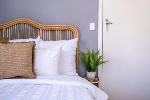 een slaapkamer met een bed met witte kussens en een plant bij Kings Beach Coastal Getaway, Bring the dog! in Caloundra