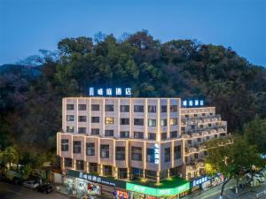 a large building with a mountain in the background at Waiting Hotel - Jiande Xin'an River Riverside in Jiande