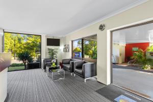 a living room with leather furniture and a large window at Comfort Inn Grammar View in Toowoomba