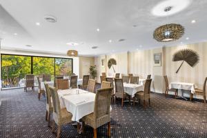 uma sala de jantar com mesas, cadeiras e janelas em Comfort Inn Grammar View em Toowoomba