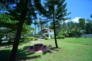 a picnic table in a park with trees and a house at SIPAYI RESORT COORG in Kushālnagar