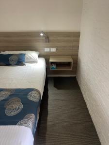 Habitación de hotel con 2 camas y pared en Aston Motel Yamba, en Yamba