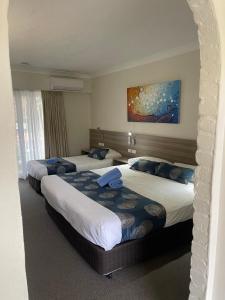 a hotel room with two beds and a painting on the wall at Aston Motel Yamba in Yamba