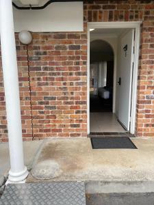 a brick building with an open door and a brick wall at Aston Motel Yamba in Yamba