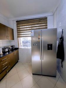 a stainless steel refrigerator in a kitchen with a window at Olive Escapes in Dar es Salaam