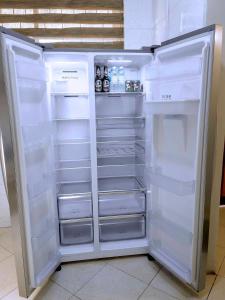 an empty refrigerator with its door open in a kitchen at Olive Escapes in Dar es Salaam