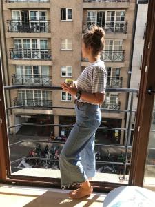 Eine Frau, die vor einem Fenster steht und ihr Handy ansieht. in der Unterkunft Appartement cosy au cœur du Zoute près de la plage in Knokke-Heist + 4 Fotos