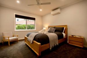 a bedroom with a bed and a window and a chair at The Bonnie Ray in Porepunkah