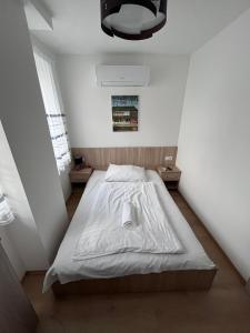 1 dormitorio pequeño con 1 cama con sábanas blancas en Május 1 Vendégház - Torony, en Torony