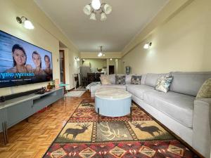 a living room with a couch and a flat screen tv at Wills House, Three Bedroom with Extra Bed in Kilimani in Nairobi