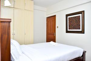 a bedroom with a white bed and a wooden cabinet at Wills House, Three Bedroom with Extra Bed in Kilimani in Nairobi