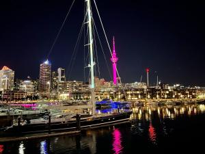 a boat docked in a harbor with a city at night at Lovely 2 bedrm apartment in Auckland's viaduct in Auckland +1 photo
