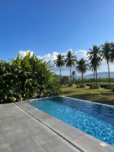 una piscina en un patio con palmeras en The Vineyard at Tanauan, en Tanauan