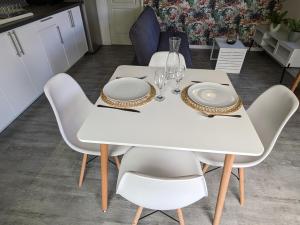 a white table with white plates and glasses on it at Au Bonheur des Makes in Saint-Louis