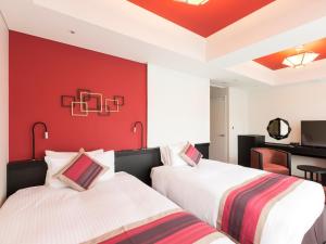 2 Betten in einem Zimmer mit roter Wand in der Unterkunft Hotel Dans Le Coeur Osaka Umeda in Osaka