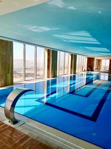 a swimming pool with blue water in a building at Windyhill Hotel in Elazığ