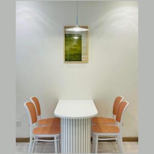 a white table with chairs and a picture on the wall at Vinhomes Landmark Apartment - CirillaHome in Ho Chi Minh City