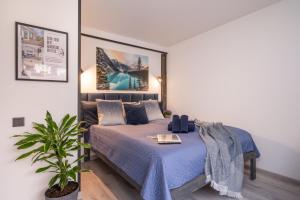 a bedroom with a bed with blue sheets and a plant at Green Garden & Parking Apartments in Rīga