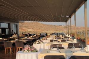 Ein großer Festsaal mit Tischen und Stühlen, im Hintergrund die Berge. in der Unterkunft Windyhill Hotel in Elâzığ