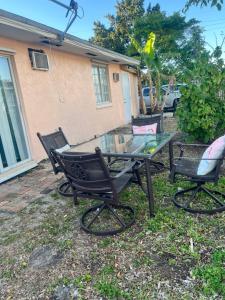 une table en verre et deux chaises devant une maison dans l'établissement Kp Paradise, à North Miami