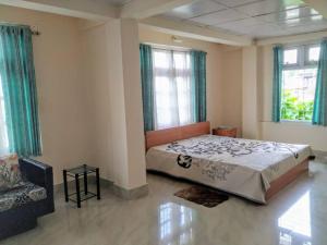 a bedroom with a bed and two windows and a couch at Two Rooms- Mountain View Apartment with Wi-Fi in Kohīma