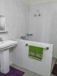 - une salle de bains blanche pourvue d'un lavabo et d'une serviette verte dans l'établissement Two Rooms- Mountain View Apartment with Wi-Fi, à Kohīma