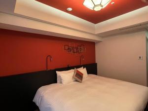 una camera con un letto bianco con una parete rossa di Hotel Dans Le Coeur Osaka Umeda ad Osaka