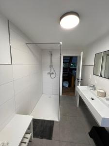 a white bathroom with a shower and a sink at Traumfabrik Eifel mit Sauna & Whirlpool in Monschau +57 photos