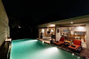 a swimming pool at night with two red chairs at Bracha Villas Bali - CHSE Certified in Seminyak