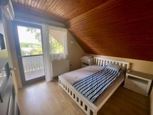 1 dormitorio con cama, techo de madera y ventana en Kisduna ház, en Dömsöd