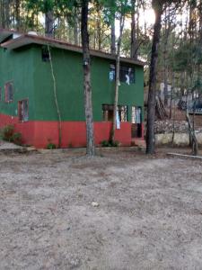 a green and red house with trees in front of it at LOS ALAMOS in San Cristóbal de Las Casas