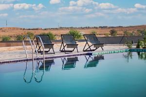 three chairs sitting next to a swimming pool at Desert Heritage Luxury Camp And Resort in Jaisalmer