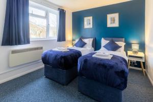 2 camas en una habitación con paredes azules en Thames, Cambridge - Long stay - Contractors - Relocators, en Cambridge