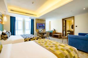 um quarto de hotel com duas camas e uma sala de estar em Mehood Theater Hotel, Lhasa em Lassa