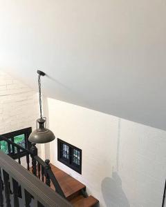 un escalier avec une lampe suspendue à un mur de briques blanches dans l'établissement บ้านสมดุลมิตร Hidden Private White Brick House Rayong, à Rayong