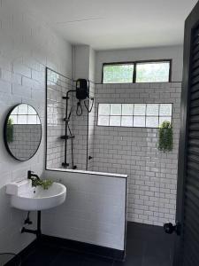 La salle de bains blanche est pourvue d'un lavabo et d'un miroir. dans l'établissement บ้านสมดุลมิตร Hidden Private White Brick House Rayong, à Rayong