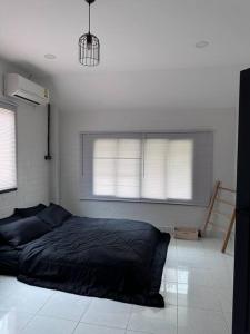 un letto in una camera da letto con due finestre di บ้านสมดุลมิตร Hidden Private White Brick House Rayong a Rayong