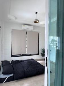 una camera con un letto nero e una parete bianca di บ้านสมดุลมิตร Hidden Private White Brick House Rayong a Rayong