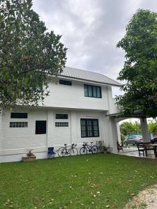 una casa bianca con due biciclette parcheggiate di fronte di บ้านสมดุลมิตร Hidden Private White Brick House Rayong a Rayong