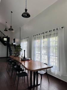 - une salle à manger avec une table et des chaises en bois dans l'établissement บ้านสมดุลมิตร Hidden Private White Brick House Rayong, à Rayong
