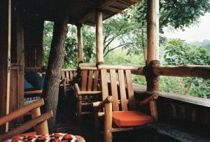 a porch of a house with a chair and a tree at Bwindi My Home in Kinkizi