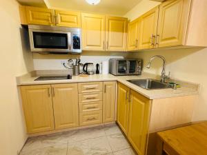 Kuchnia z drewnianymi szafkami, zlewem i kuchenką mikrofalową w obiekcie Scotchmere Serenity: Modern 1-Bedroom Brampton Haven w mieście Brampton